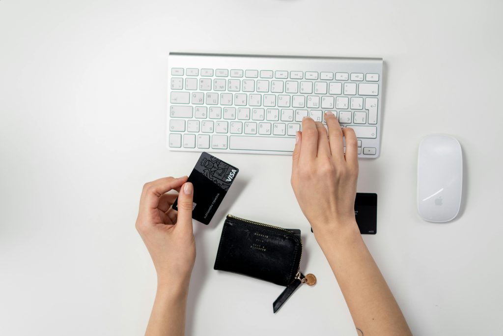 hands typing on a keyboard while holding a credit card