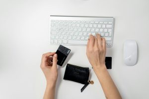 hands typing on a keyboard while holding a credit card